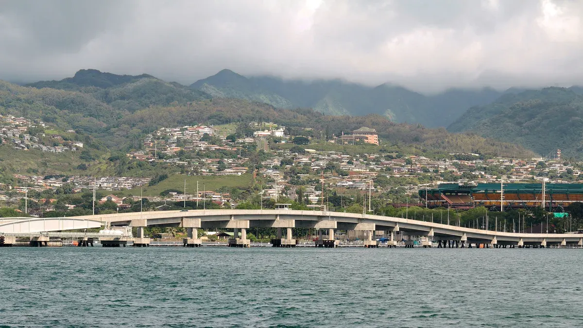 The Ford Island (Admiral Clarey) Bridge crossing Pearl Harbor seen from the water, hills and Aloha Stadium beyond, seen on Pearl Harbor tours from Honolulu